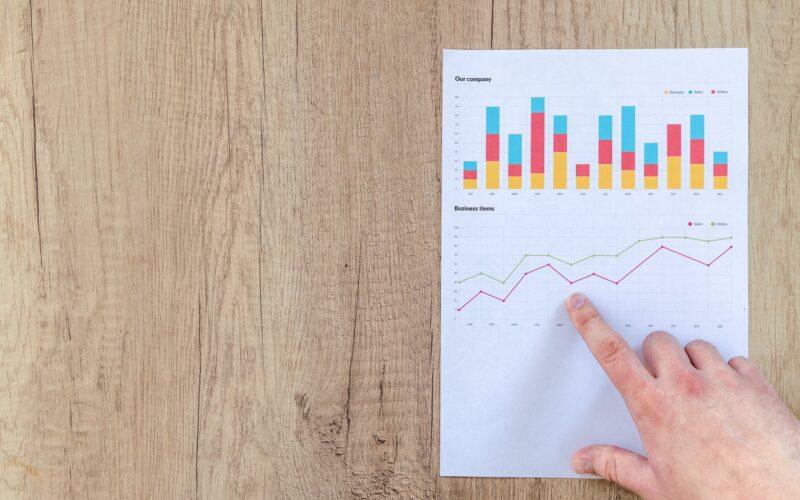 person pointing paper line graph