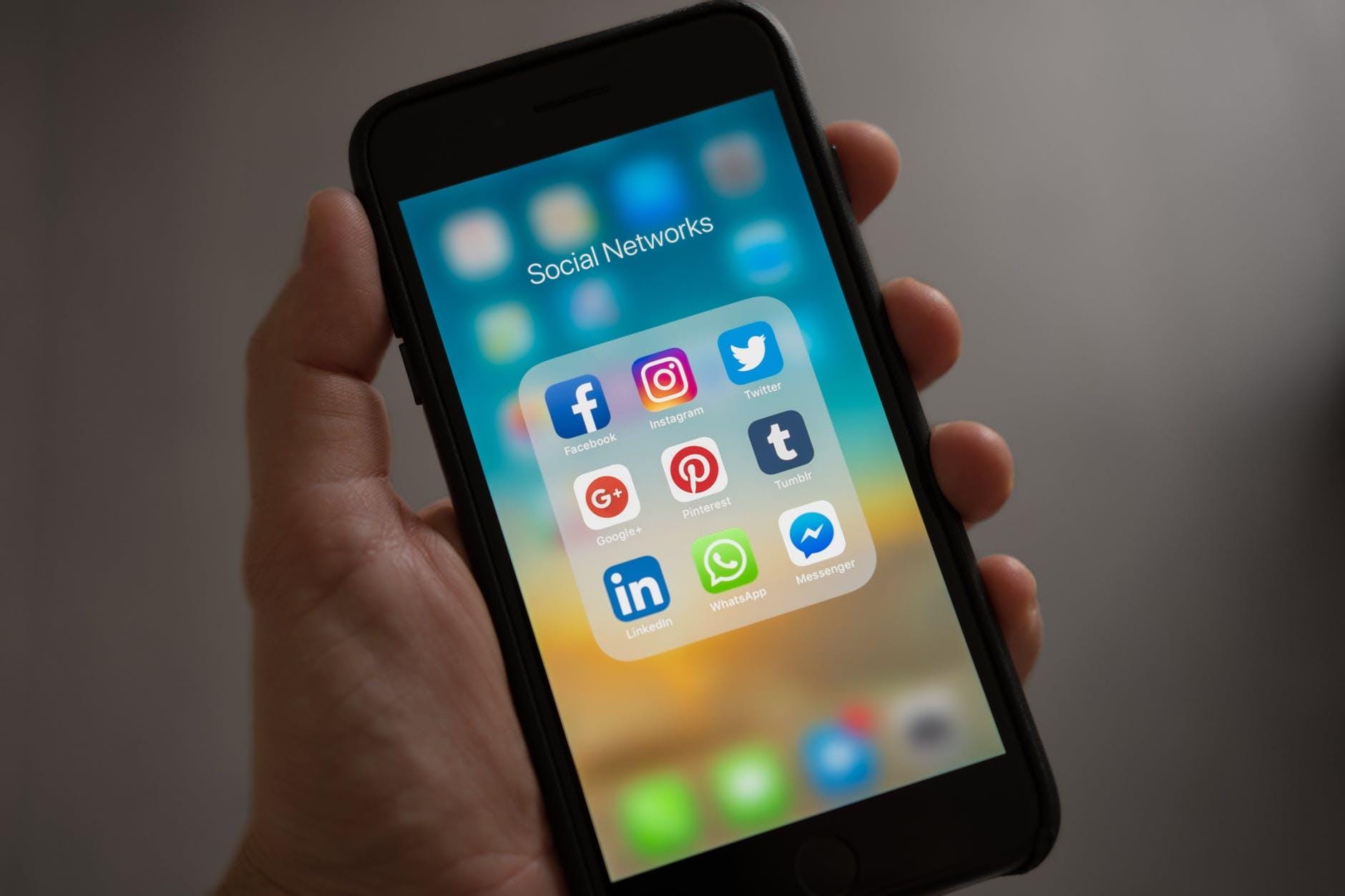 Photo by Tracy Le Blanc on Pexels.com person holding iphone showing social networks folder