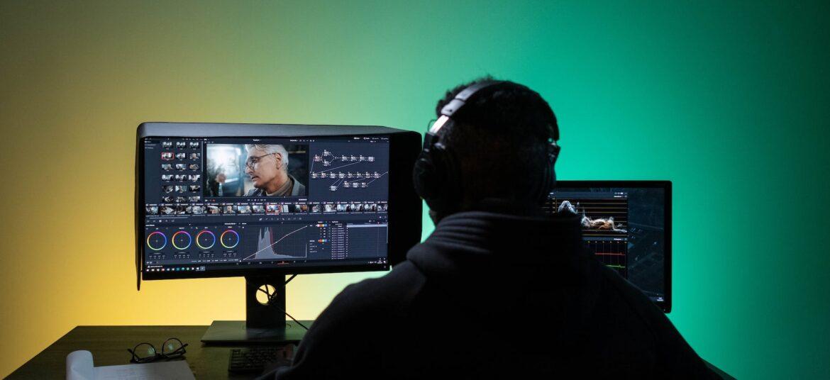 a man sitting on front of the computer while editing video