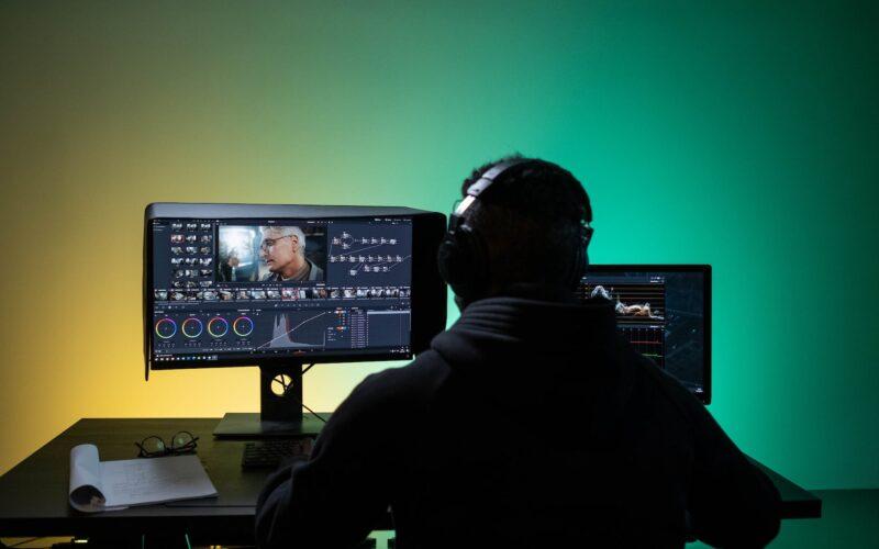 a man sitting on front of the computer while editing video